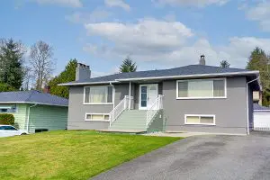 Older grey home in average neighborhood with asphalt roof. 